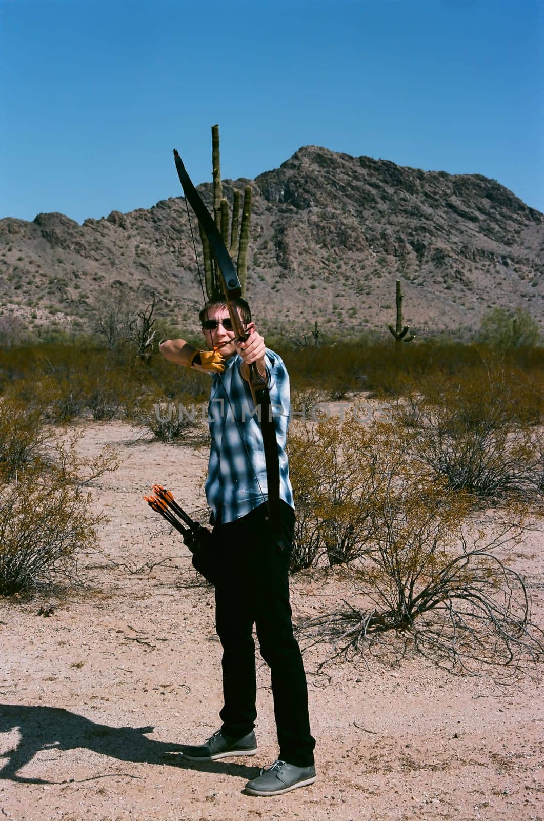 Young man shooting a bow and arrow in the desert