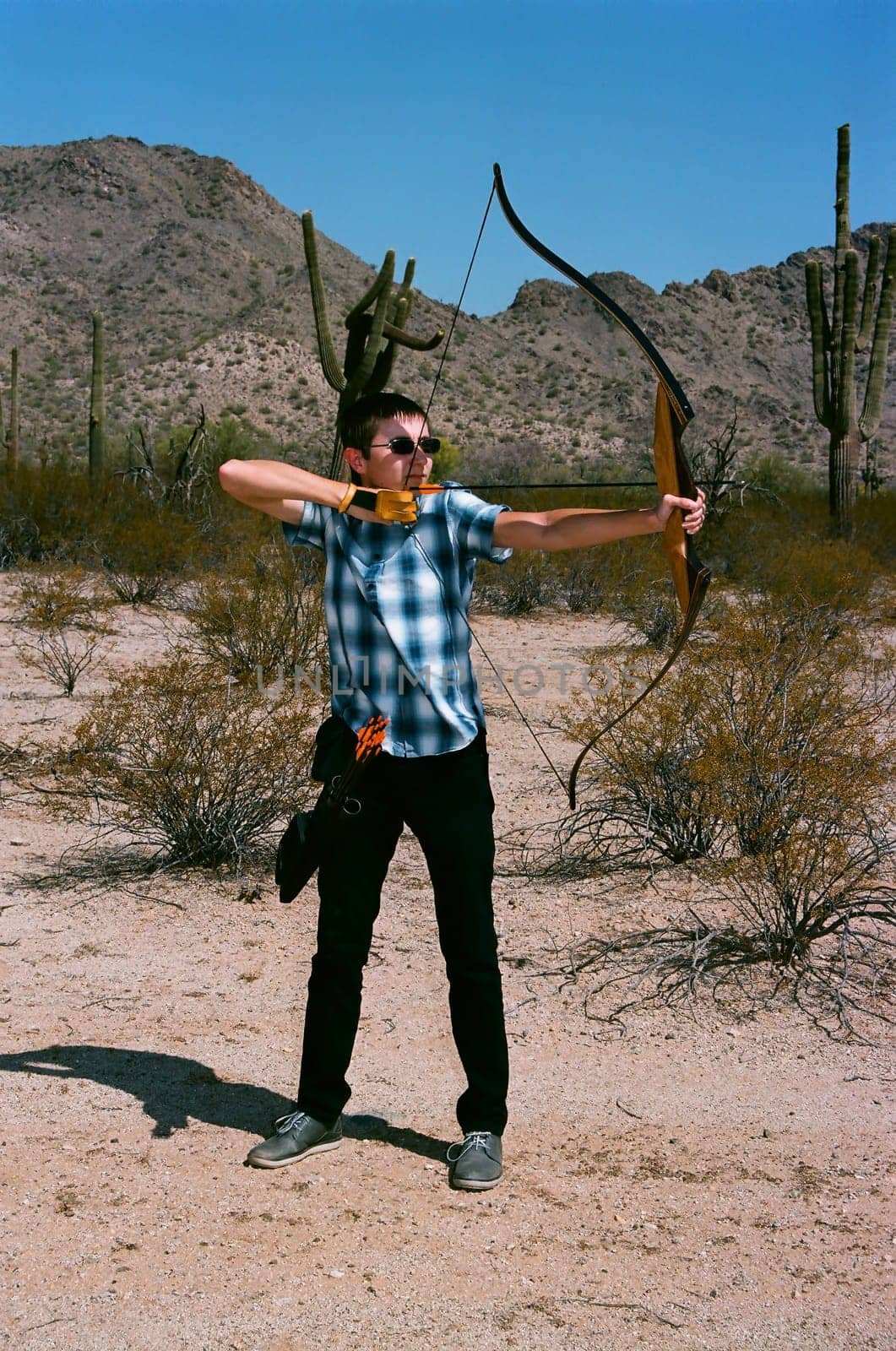 Young man shooting a bow and arrow in the desert