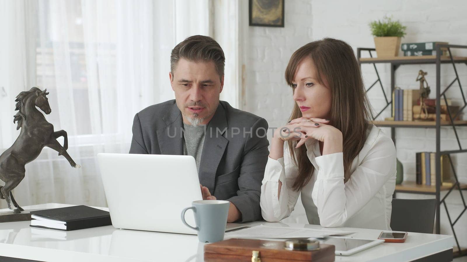 Happy business people working at desk using laptop computer, talking, working together