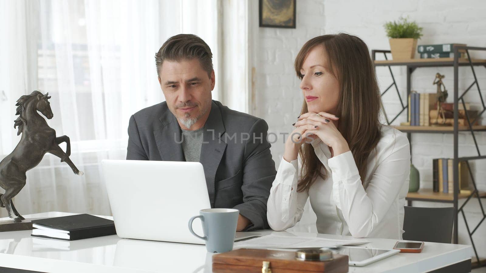 Happy business people working at desk using laptop computer, talking, working together