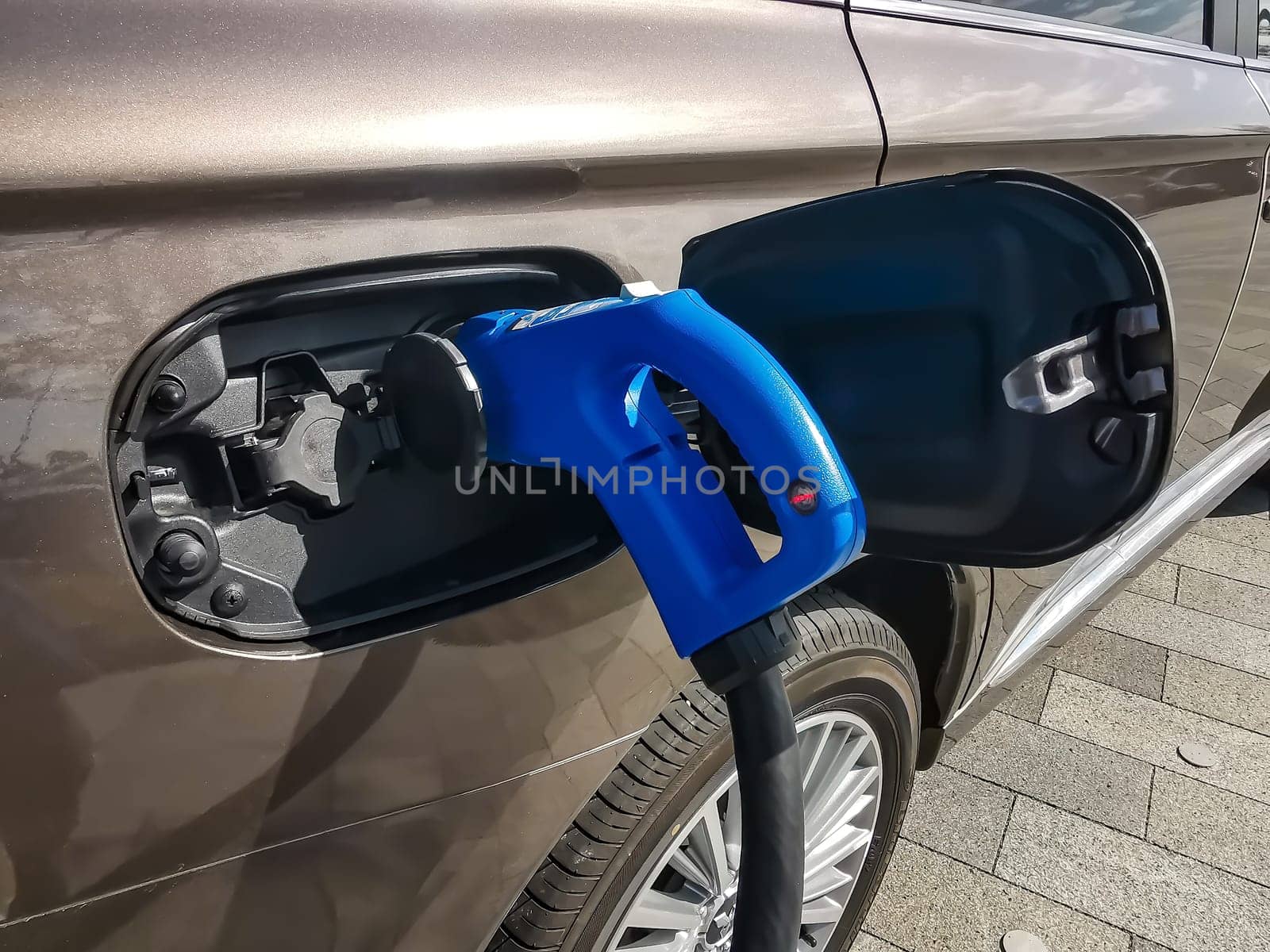 Electric car is refueled. Picture shows an electro connector and car in detail with the tank cap open