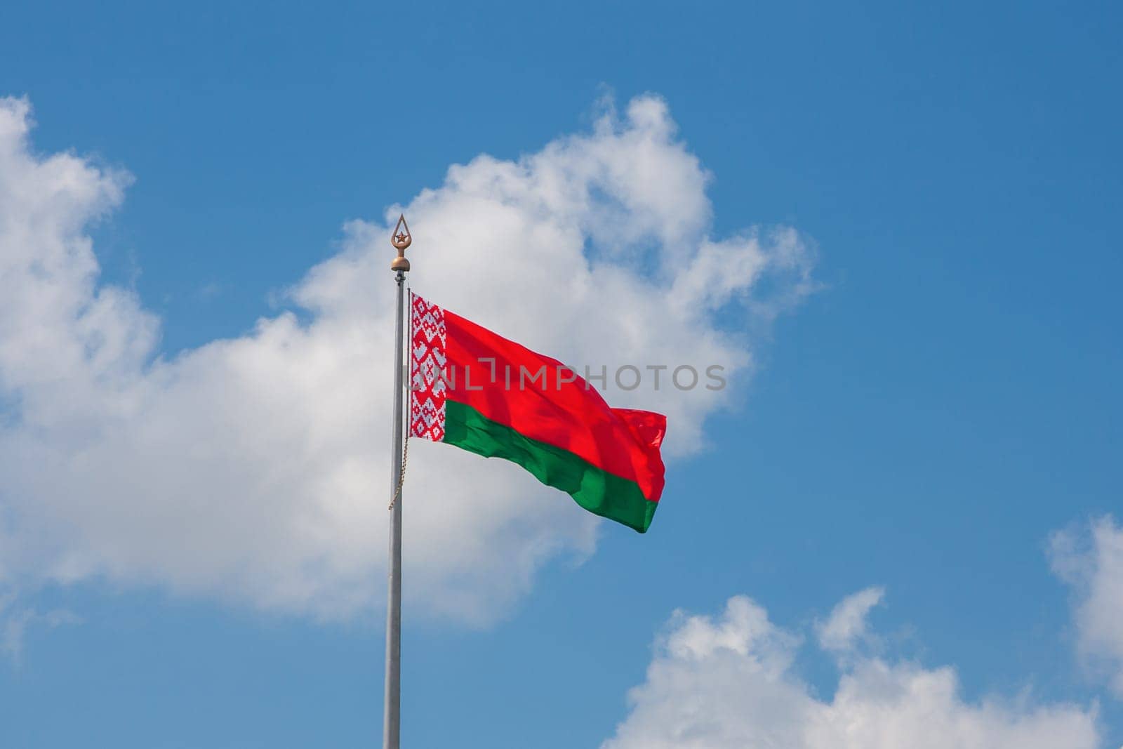 Flag of the Republic of Belarus on a background of blue sky and clouds