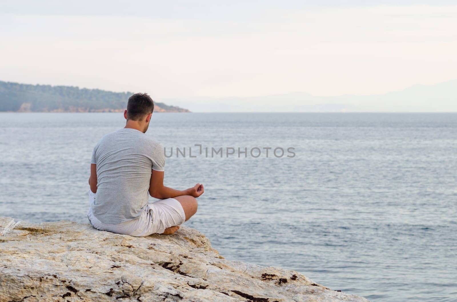 Young man sitting on the coast and meditating