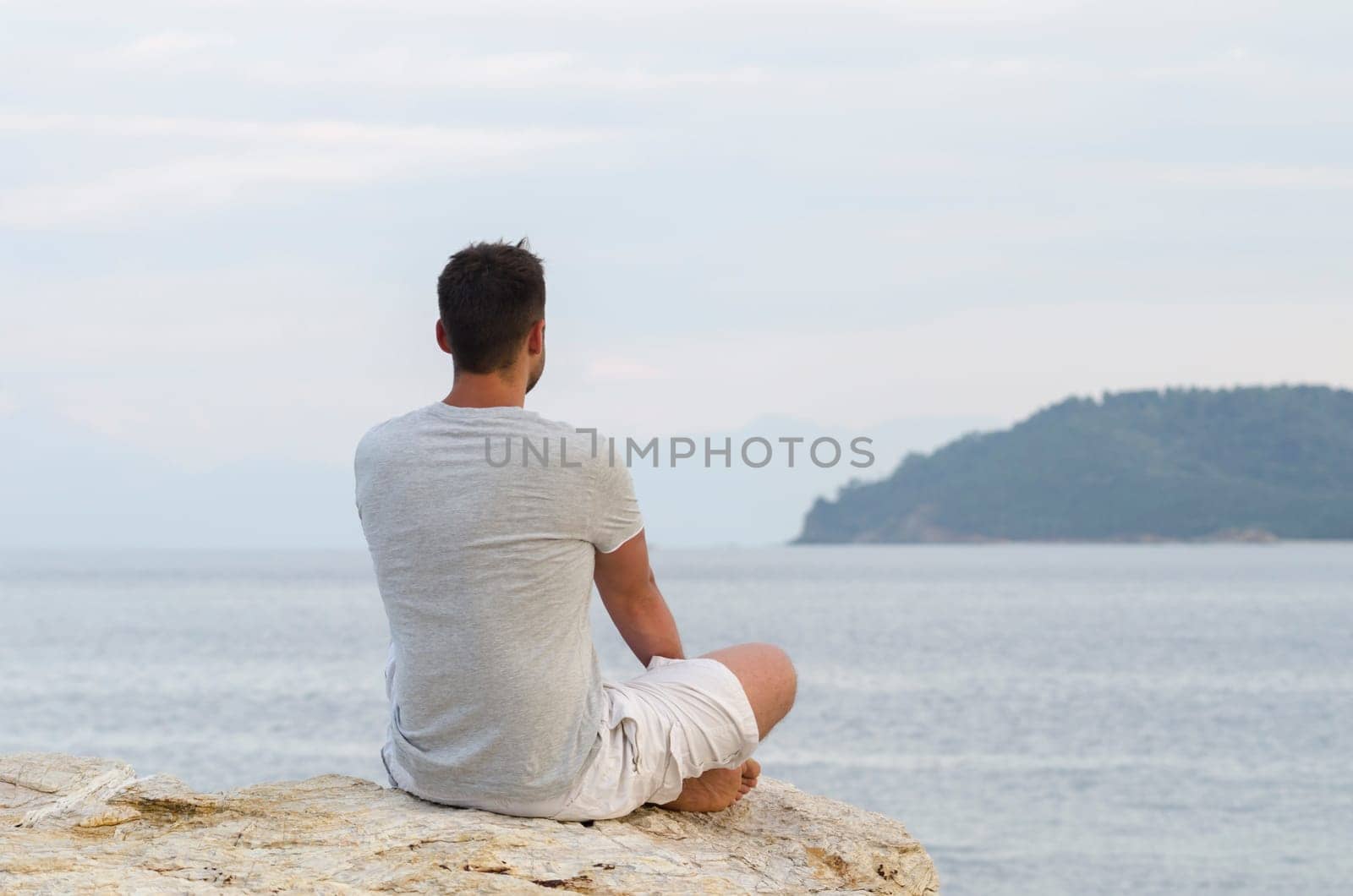 Young man sitting on the coast and meditating