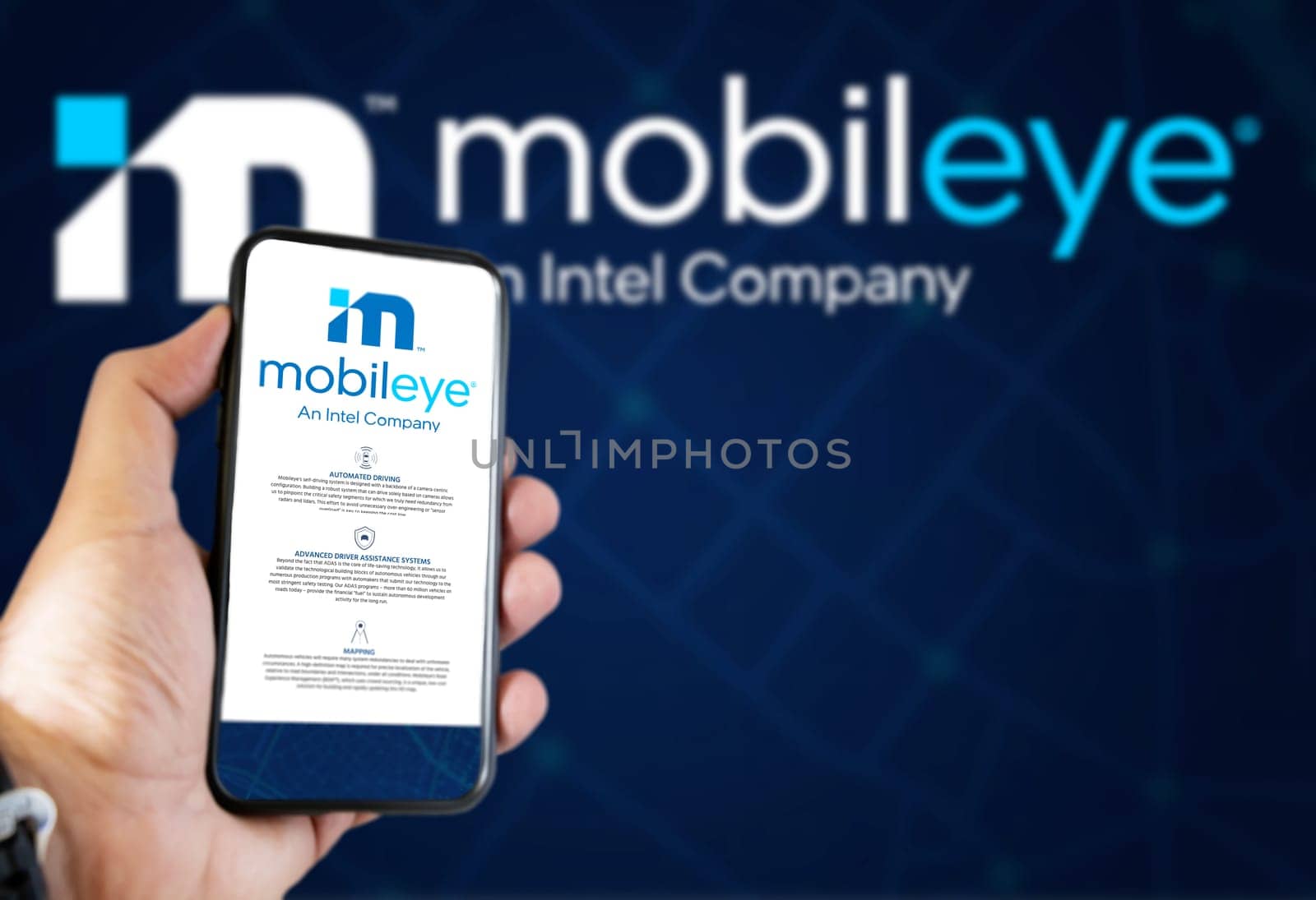 Jerusalem, ISR, March 2022: Mobileye company’s website on a phone screen. Blue background with Mobileye logo blurred in the background. Illustrative editorial. Realistic mockup. Selective focus.