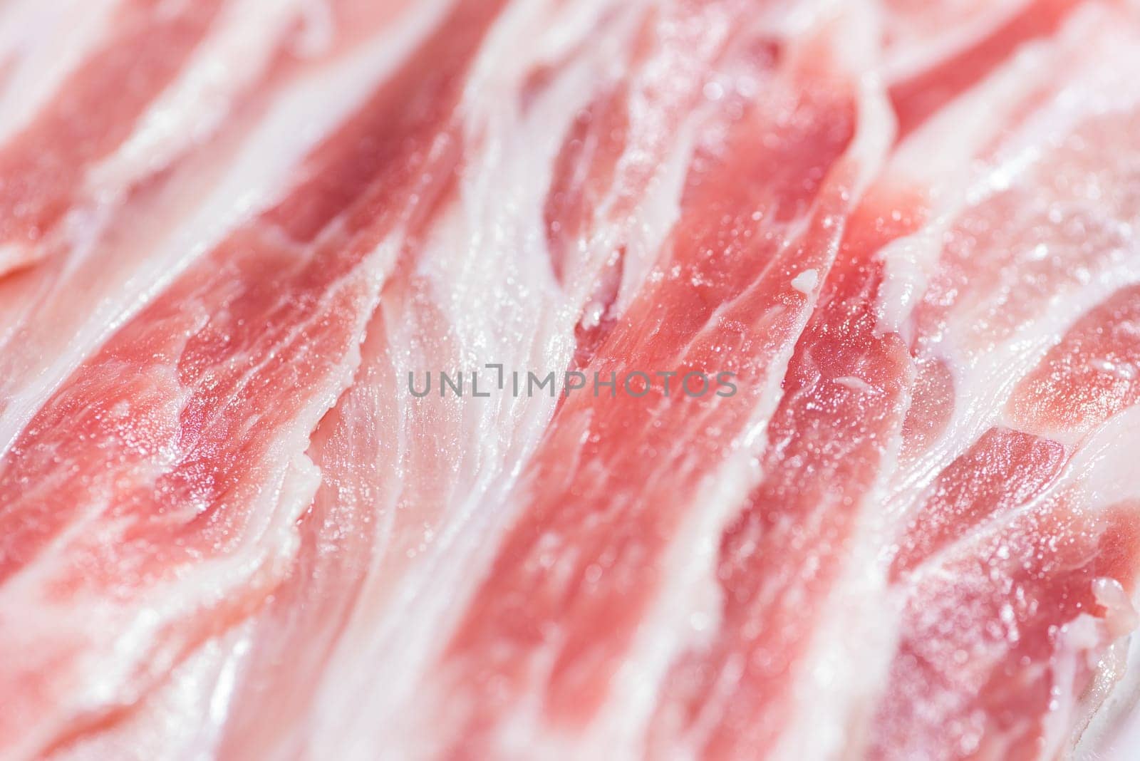 Close up top view pack bacon, pieces raw meat of fresh red pork with white fat slices are sliced into thin strips stacked on top of each other