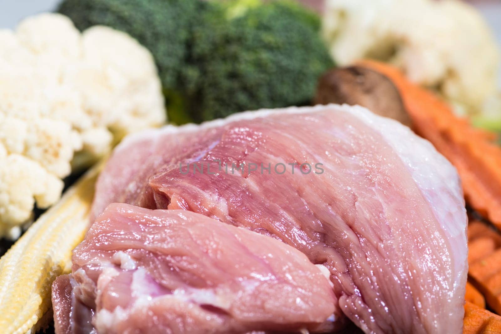 Close up piece fresh raw meat of pork and many vegetables are baby corn, broccoli flowers, mushroom, carrot, cauliflower Ingredients for food preparation cooking