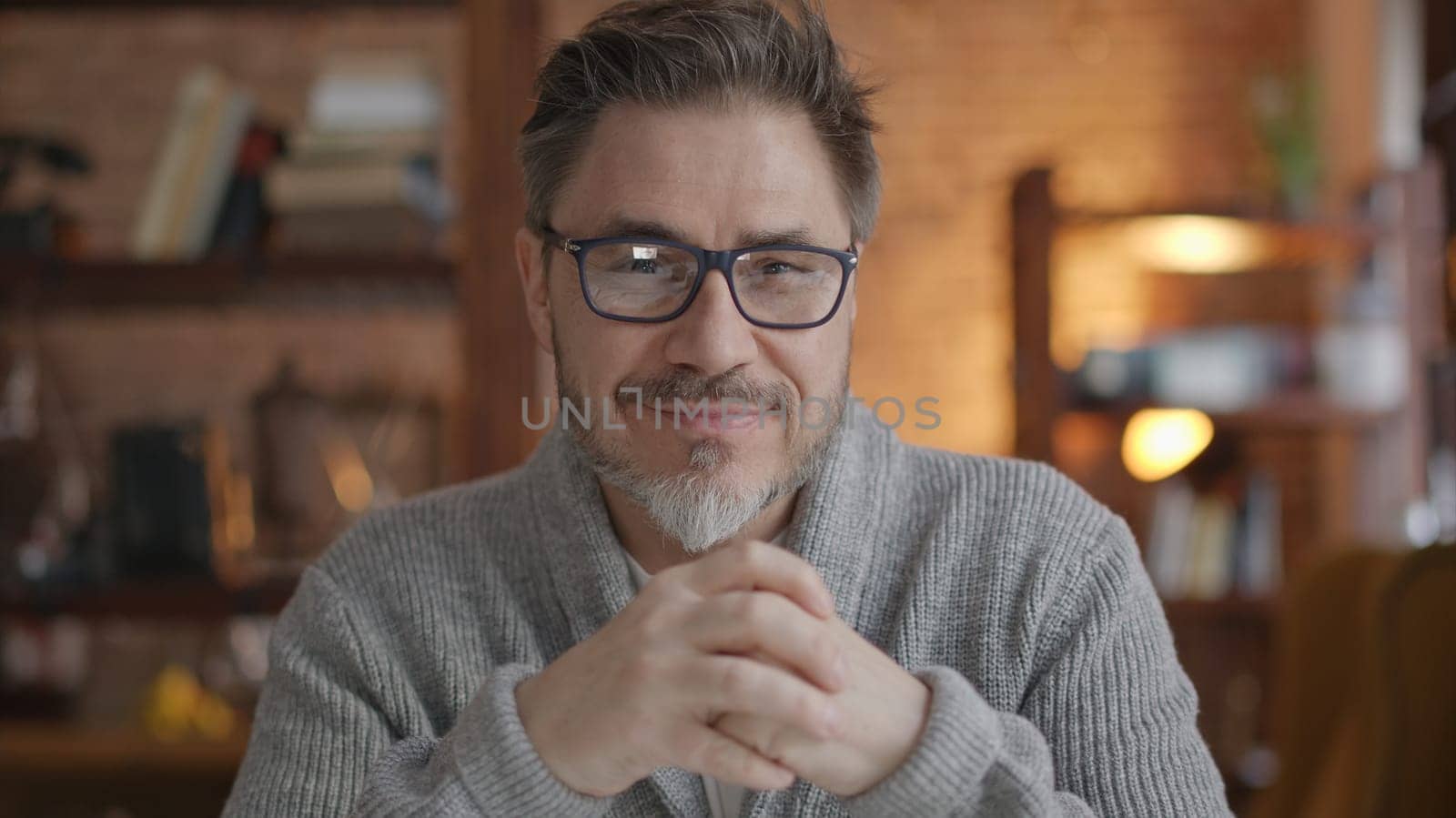 Happy bearded older man at home wearing glasses looking at camera, smiling. Portrait of mature age, middle age, mid adult man in 50s.
