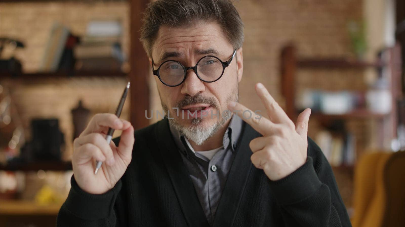 Teacher teaching online from home. Man wearing eyeglasses talking on conference call, explaining in E learning online class, lesson, training course. Mature, middle age, mid adult in 50s.
