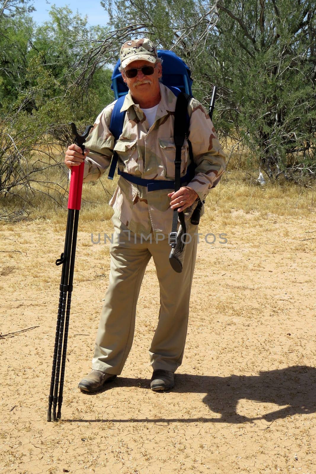 Senior hunter in sonora desert carrying rifle and pack