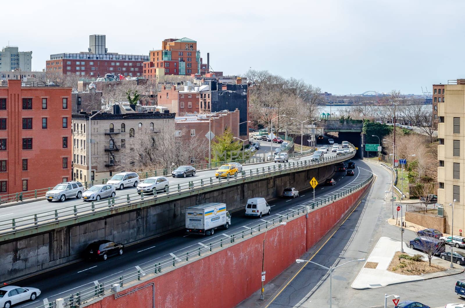 Lots of car traffic on the street crossing on different levels entering and exiting Brooklyn Bridge, Manhattan, New York City, during daytime, horizontal