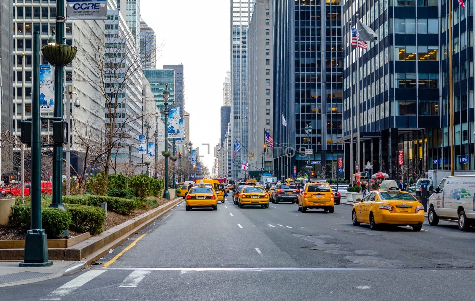 Yellow Taxi Cabs on a wide street in Manhattan rear view in the evening, lots of traffic on the street, Skyscraper on the left and right side, New York City, horizontal