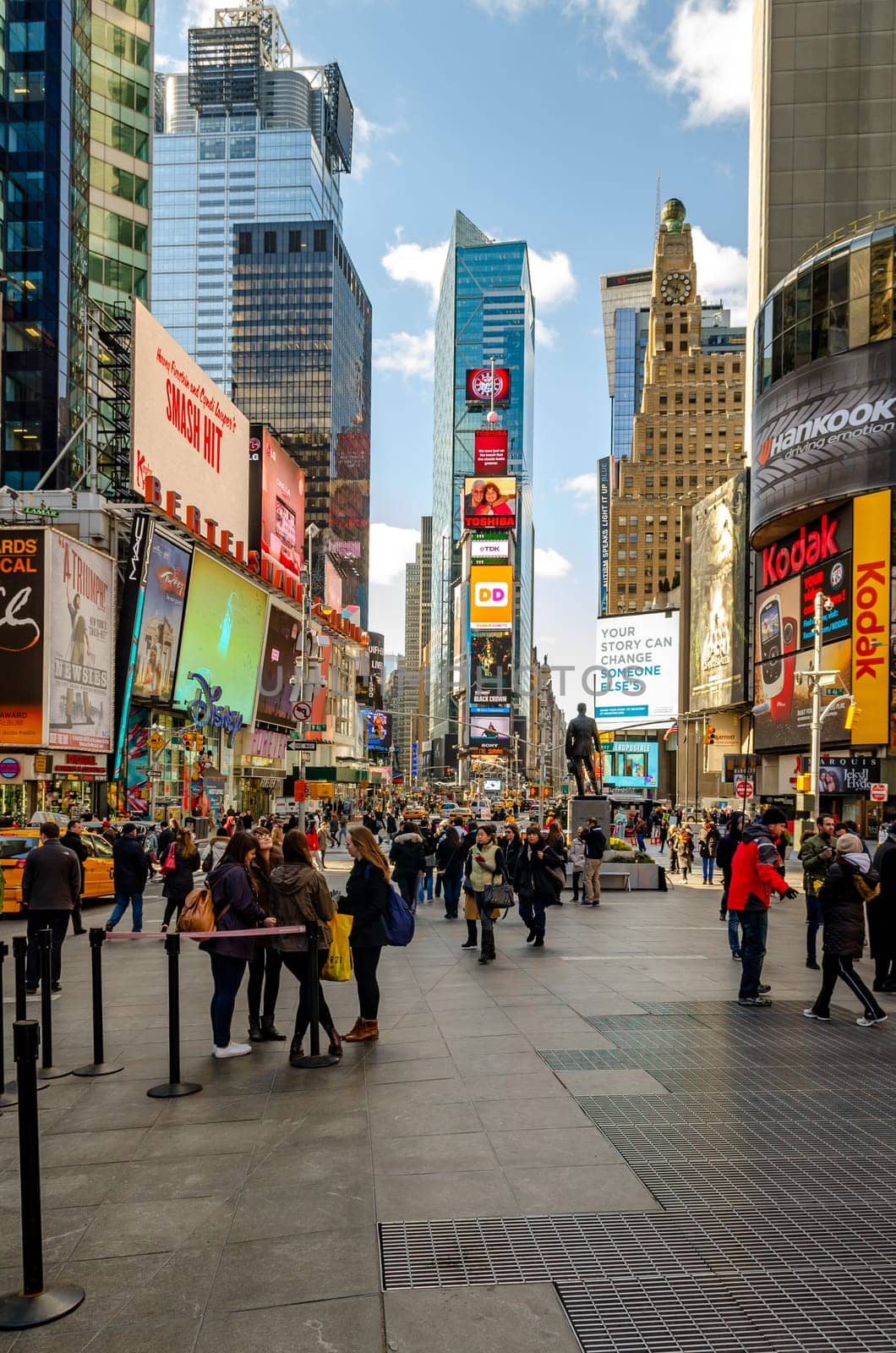 Crowded Time Square New York City with lots of People standing and walking around in the evening, Skyscraper with advertisement on it, vertical