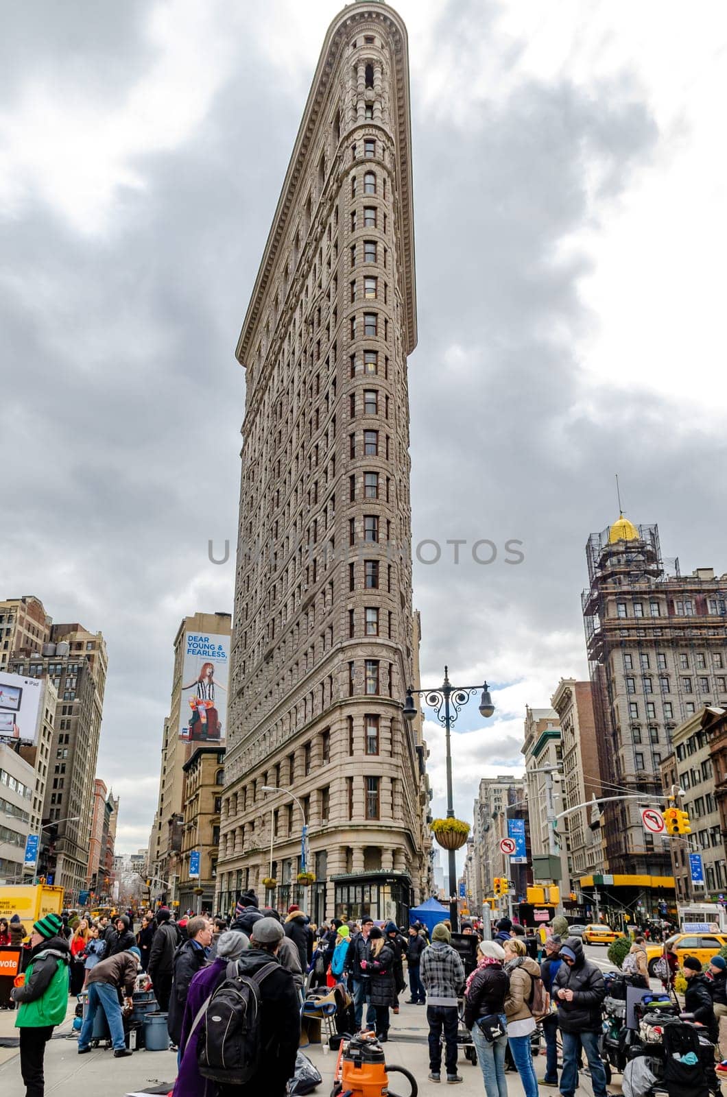 Flatiron Building New York City with lots of People standing in the forefront low angle view during daylight, overcast, vertical