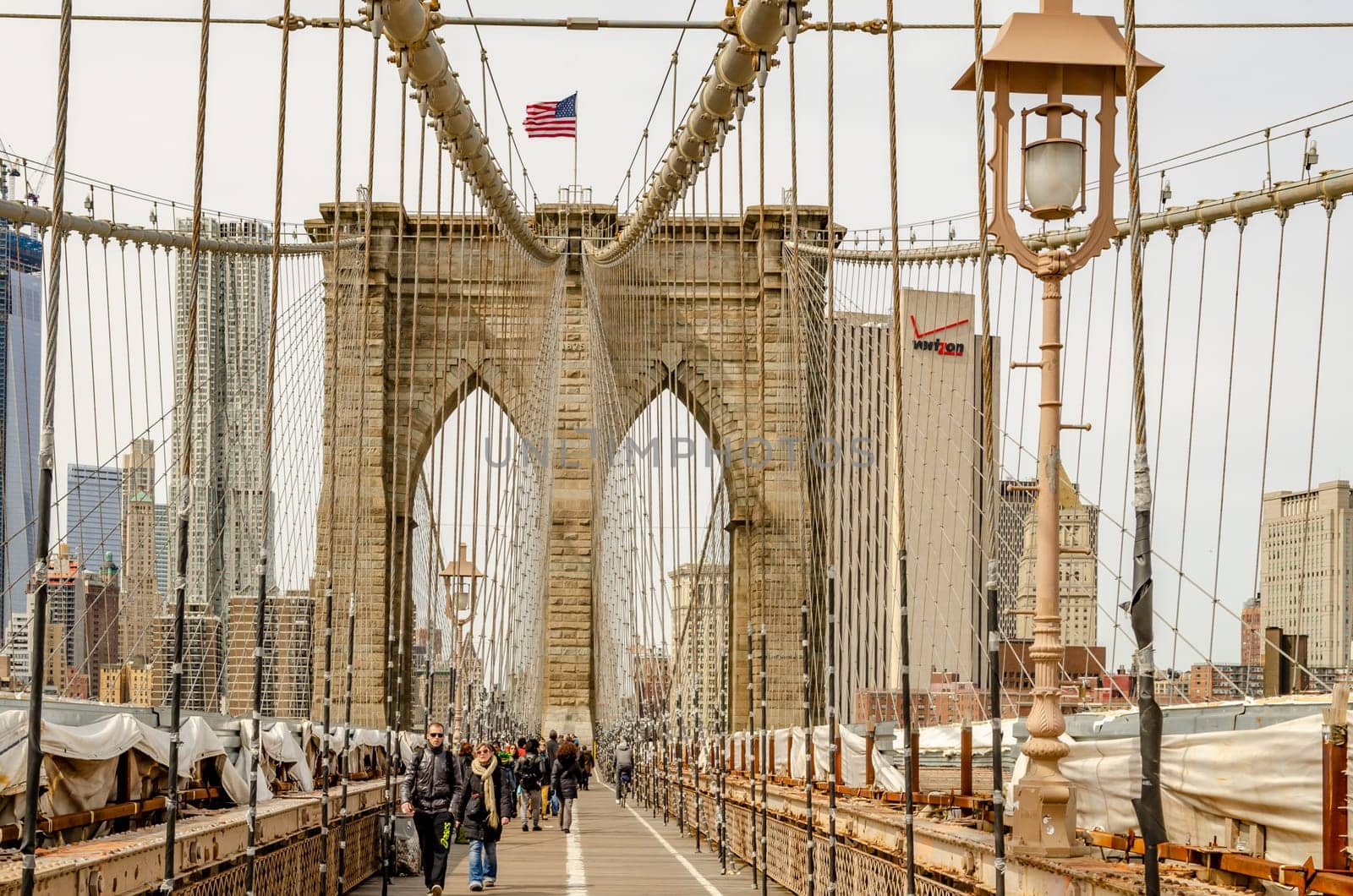 People walking and cycling on Brooklyn Bridge during winter, New York City, Street Light and wire in the forefront, horizontal
