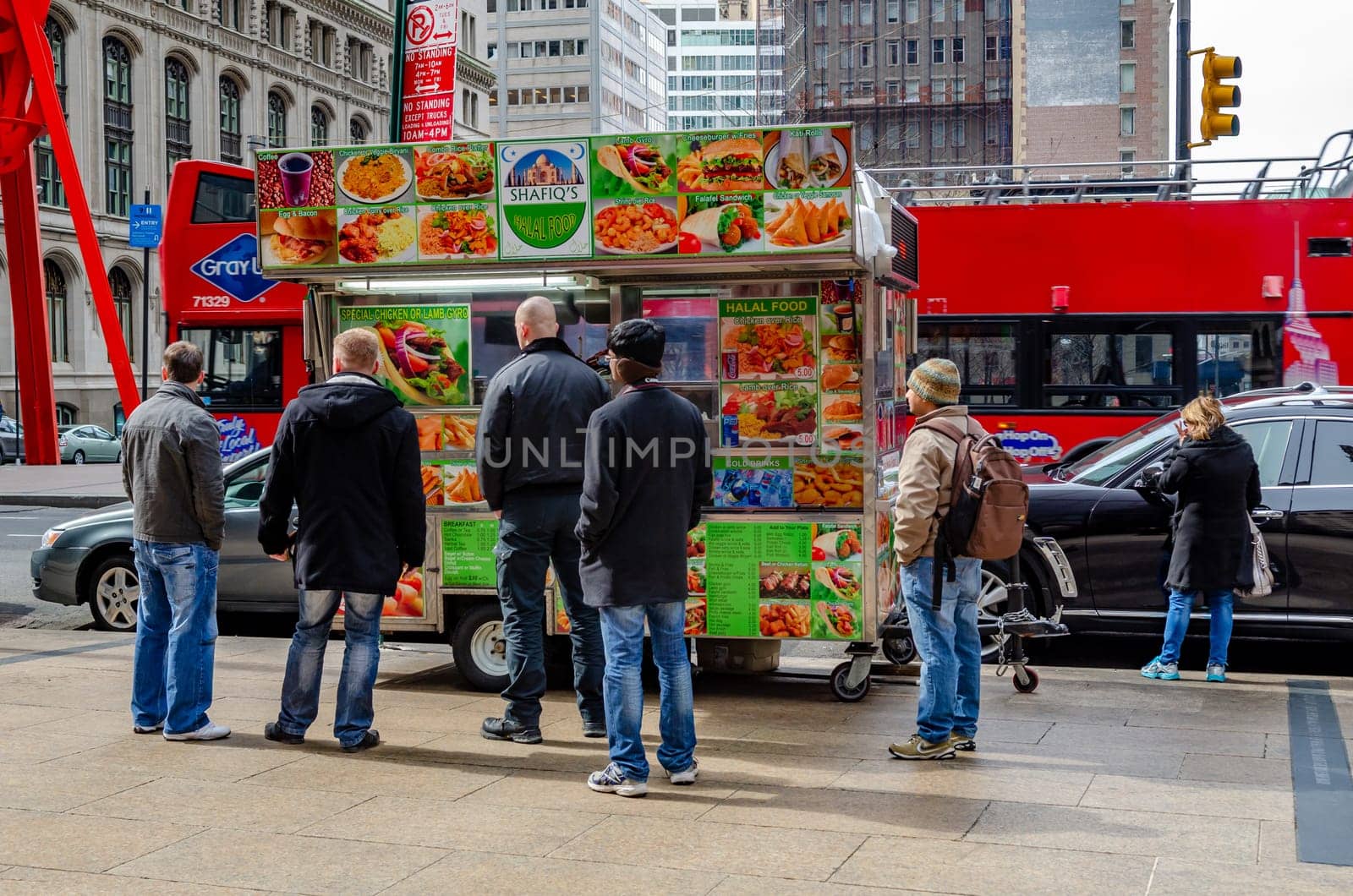 People waiting in line in front of Shafiq's Halal Street Food Truck standing on a sidewalk in Manhattan rear view, New York City, during winter, horizontal