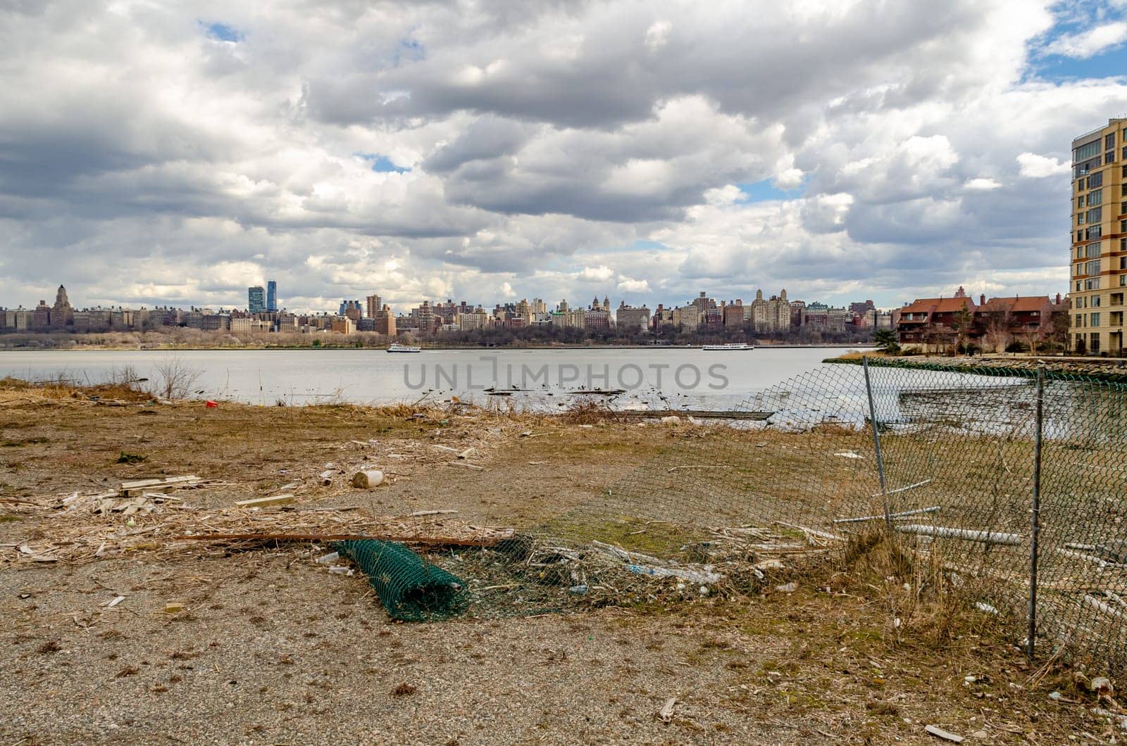 View of Manhattan with Hudson river, Construction area fence and river bank in the forefront, view from North Bergen, New Jersey, during a sunny winter day, horizontal