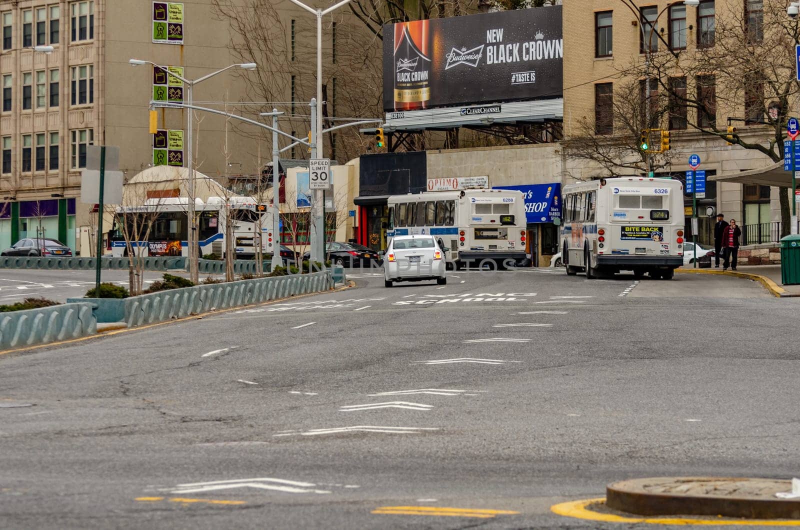 Staten Island, New York City, Buses and cars leaving the Ferry Terminal Station, rear view, during winter day retail stores and advertisement in the background, horizontal