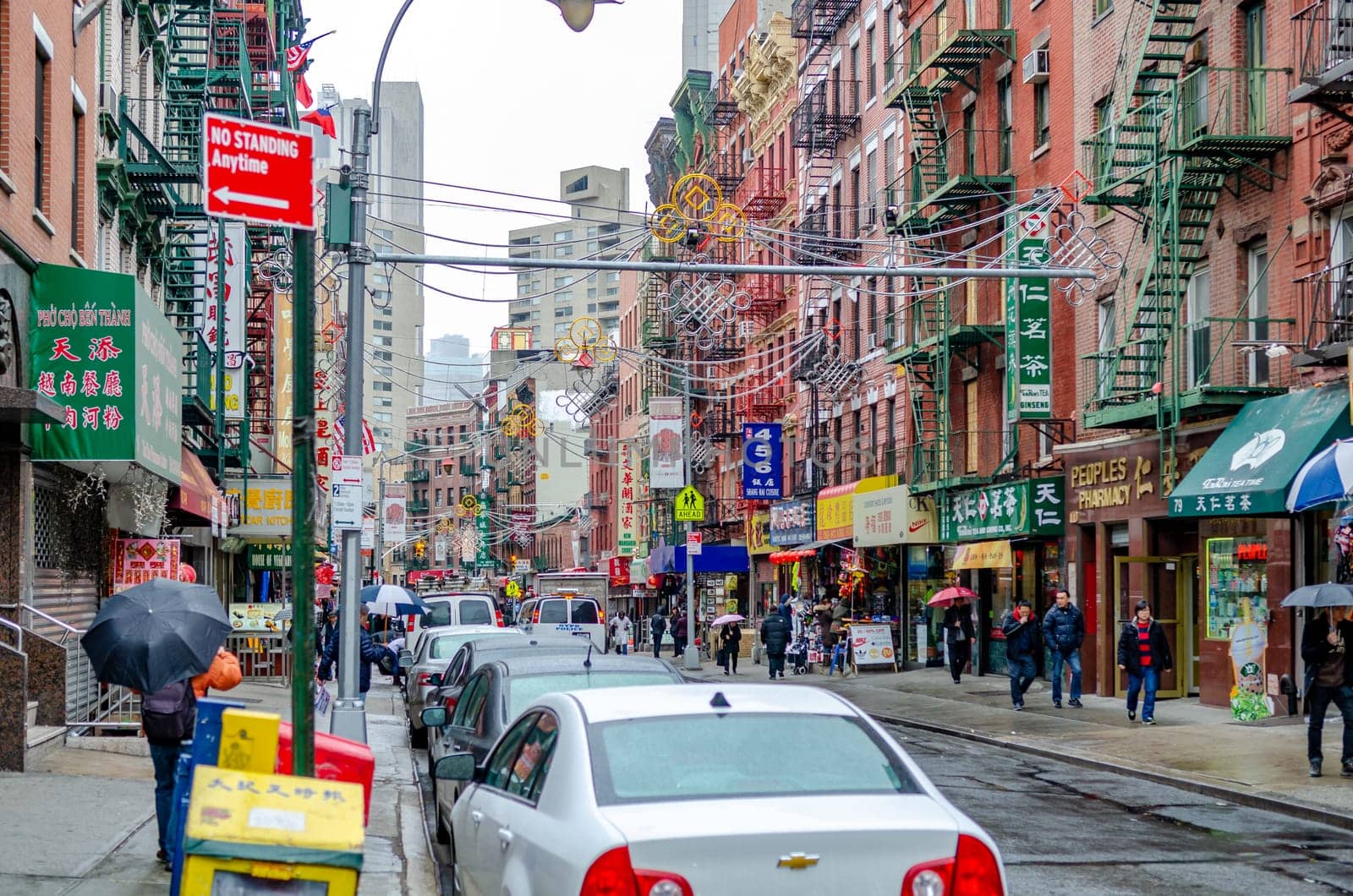 China Town New York City with retail stores and people walking with umbrellas on the sidewalk, during rainy winter day with overcast, horizontal