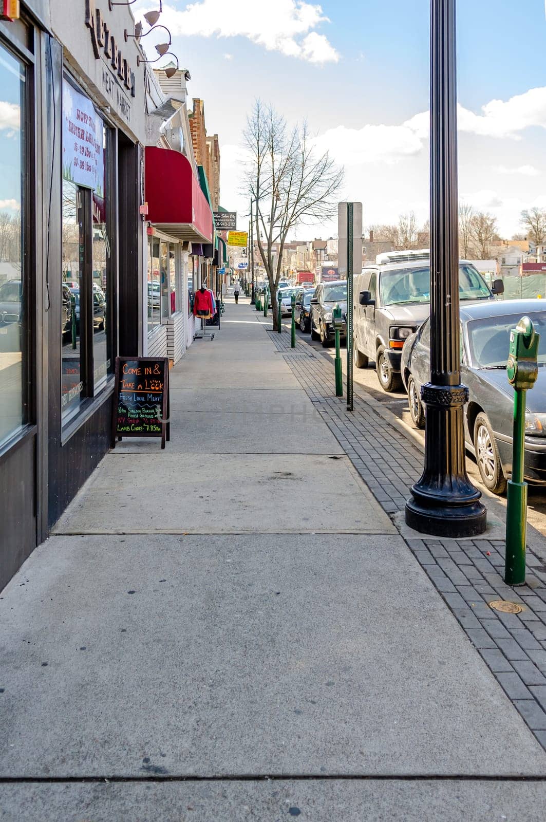 Retail Stores at Center of the City near Cliffside Park, New Jersey, during a sunny winter day, lots of cars parked next to the street, vertical