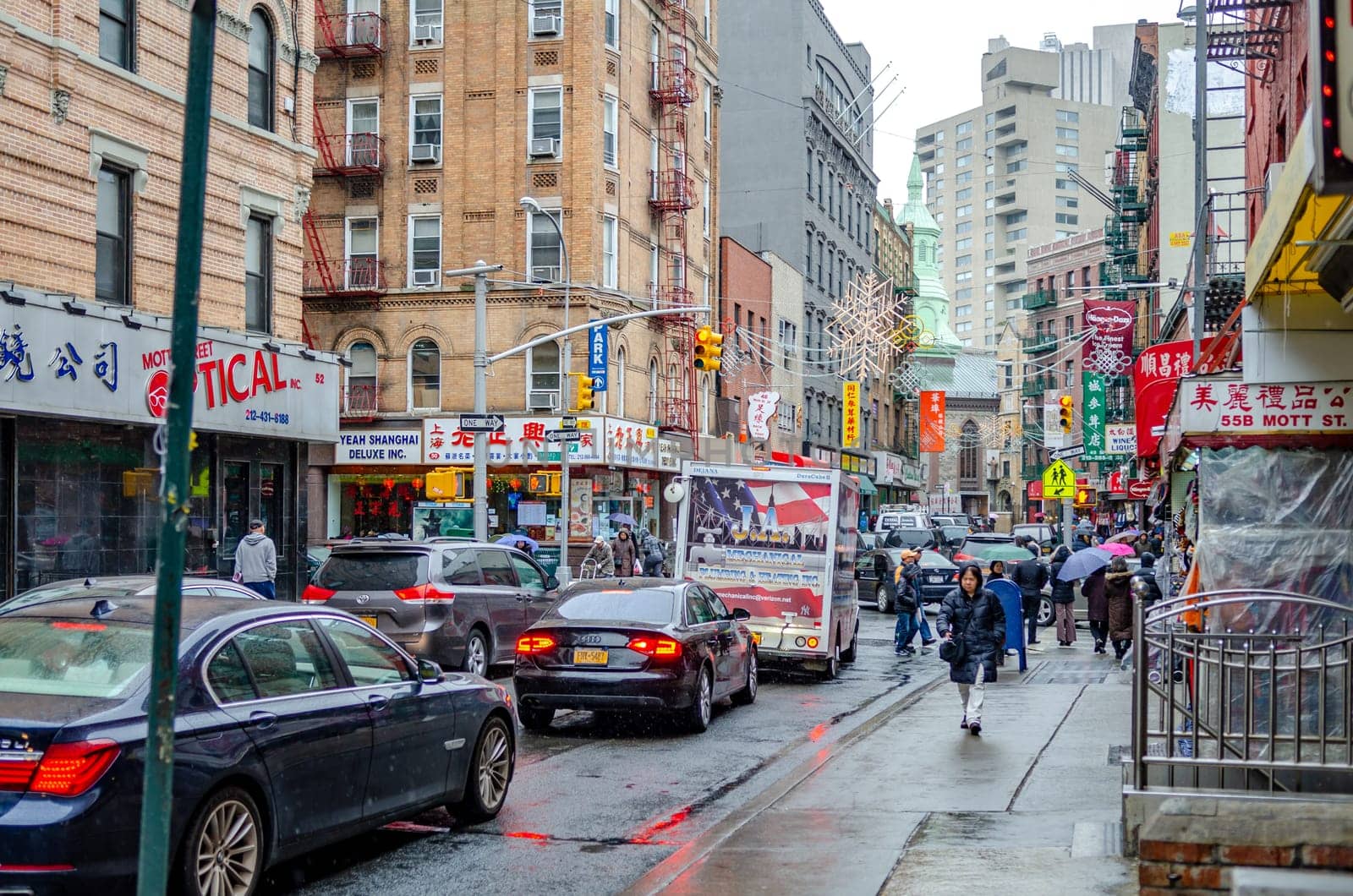 Traffic Jam at China Town New York City, red traffic light, rainy winter day with People walking with umbrellas on the sidewalk of the street, during rainy winter day with overcast, horizontal