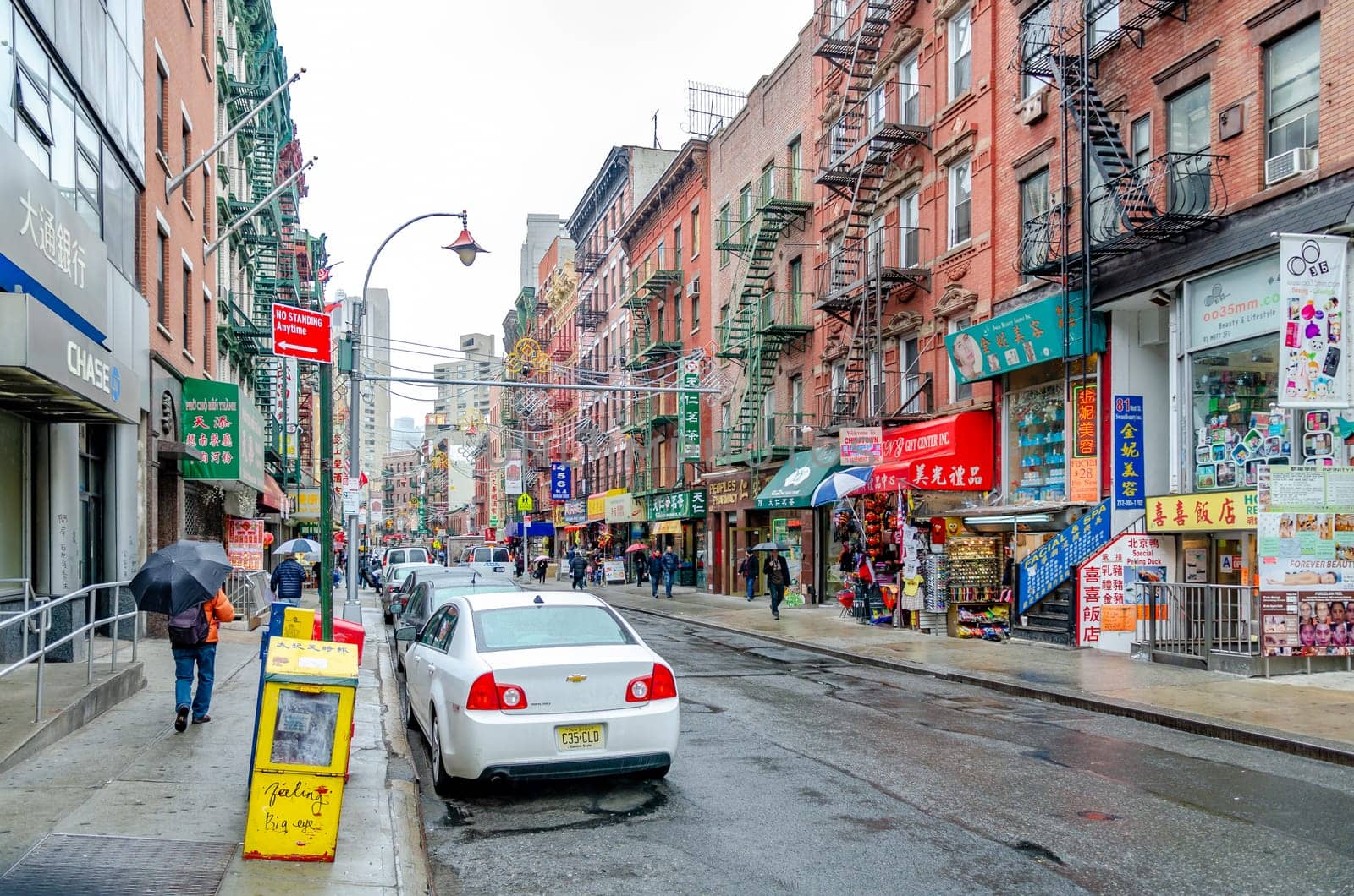 China Town New York City with retail stores and people with umbrella walking on the sidewalk, during rainy winter day with overcast, horizontal