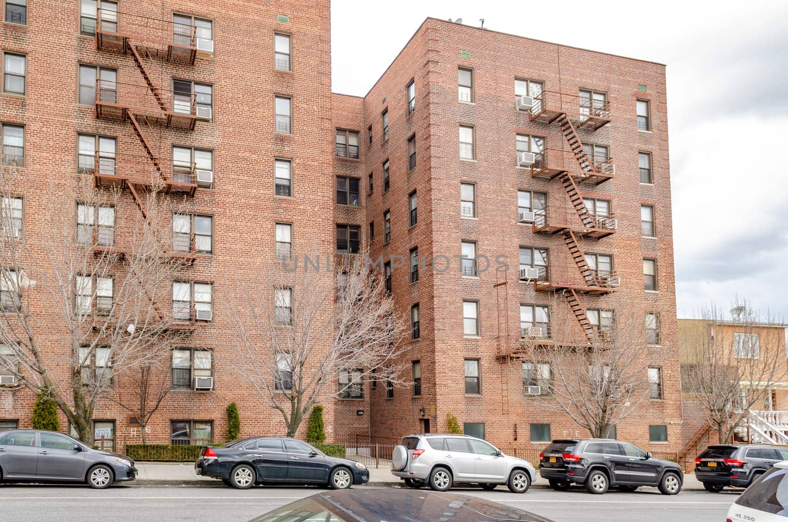 Brown Residential Building in Coney Island with lots of cars parked in front on the street, New York City during winter, horizontal