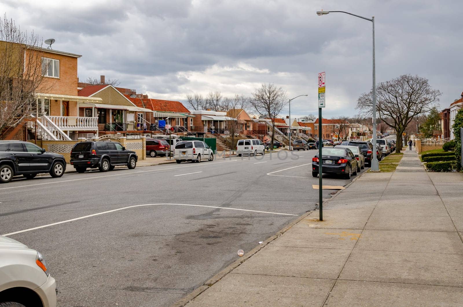 Residential Area in Queens, City street with parked cars and lots of different houses, New York City during  overcast winter day, horizontal
