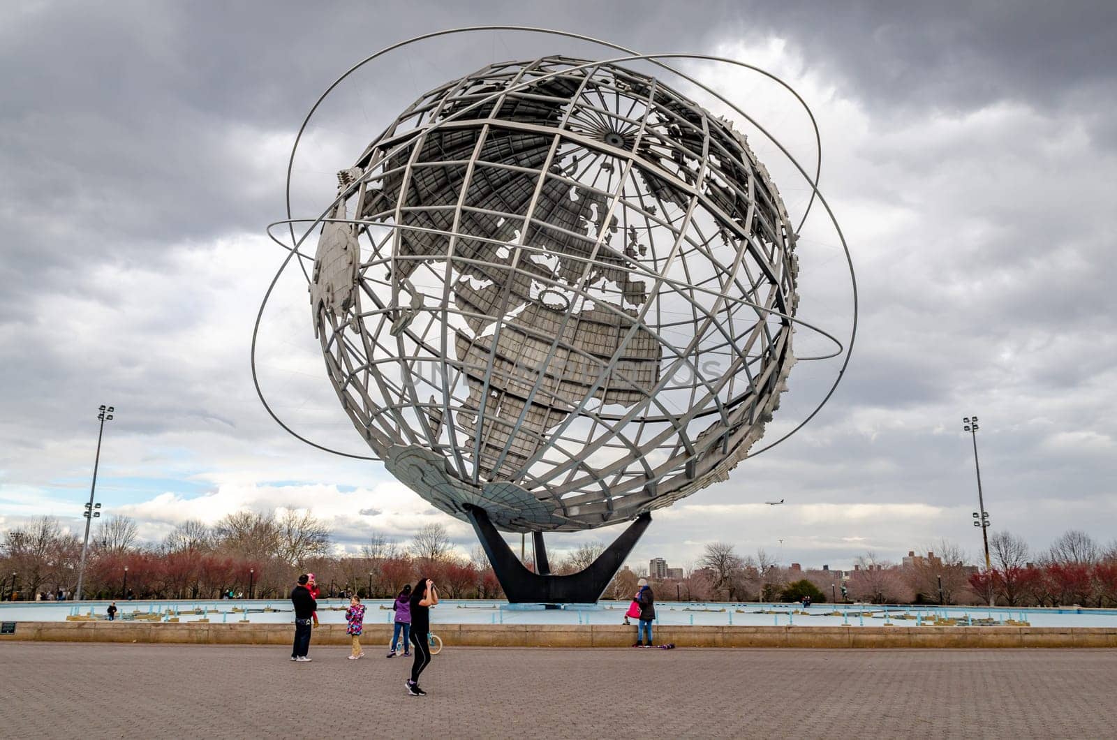 Unisphere at Flushing-Meadows-Park with people standing and walking in front, Queens, New York City during overcast winter day, horizontal