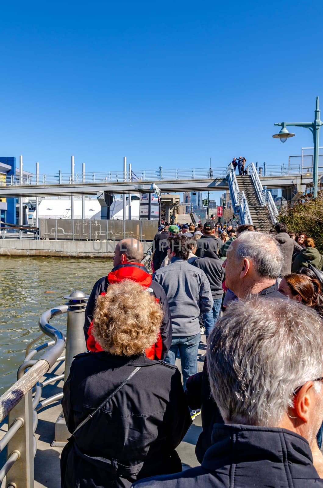 People, tourist waiting in line in front of the Entrance of Intrepid Sea-Air-Space Museum, New York City during sunny winter day with clear sky, vertical