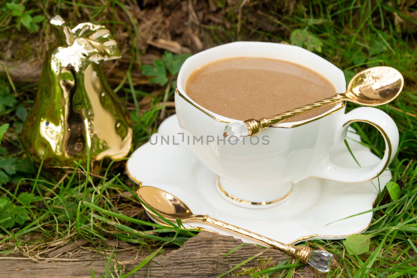 White cup of hot coffee on the grass , good morning sujet