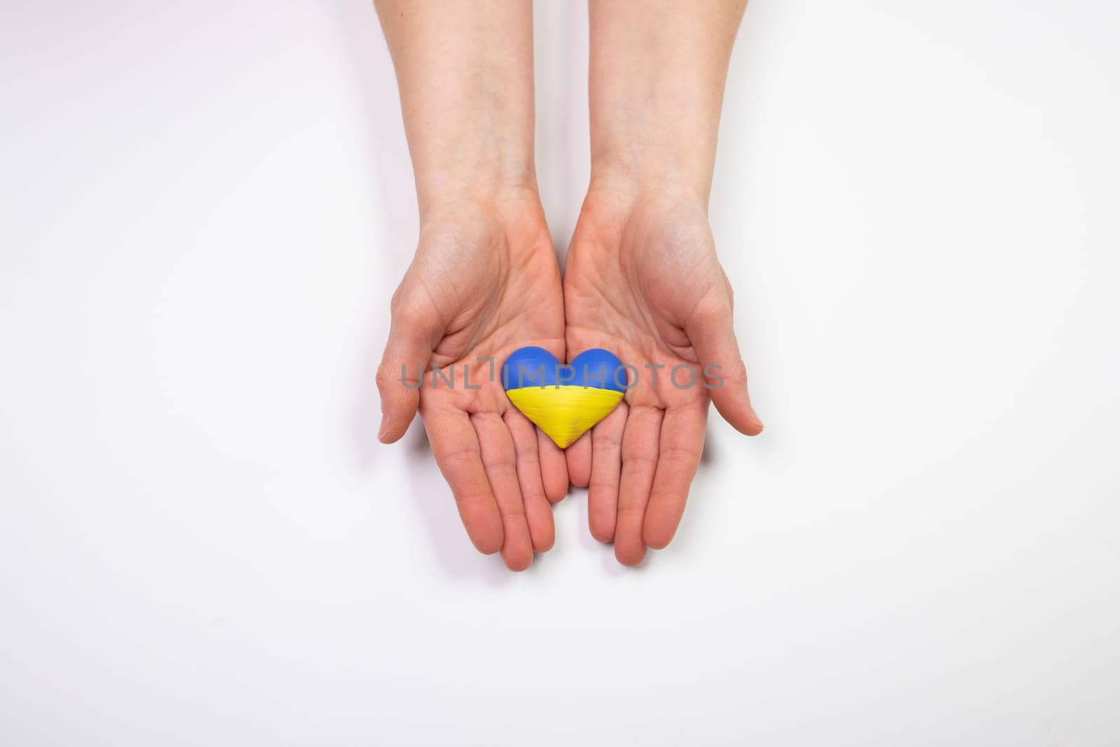 Heart shaped flag of Ukraine in female hands. The concept of solidarity with the citizens of Ukraine.