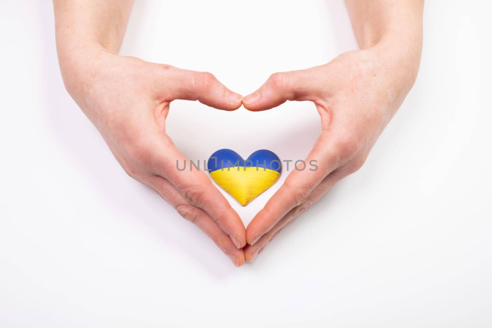 Heart shaped flag of Ukraine in female hands. The concept of solidarity with the citizens of Ukraine.