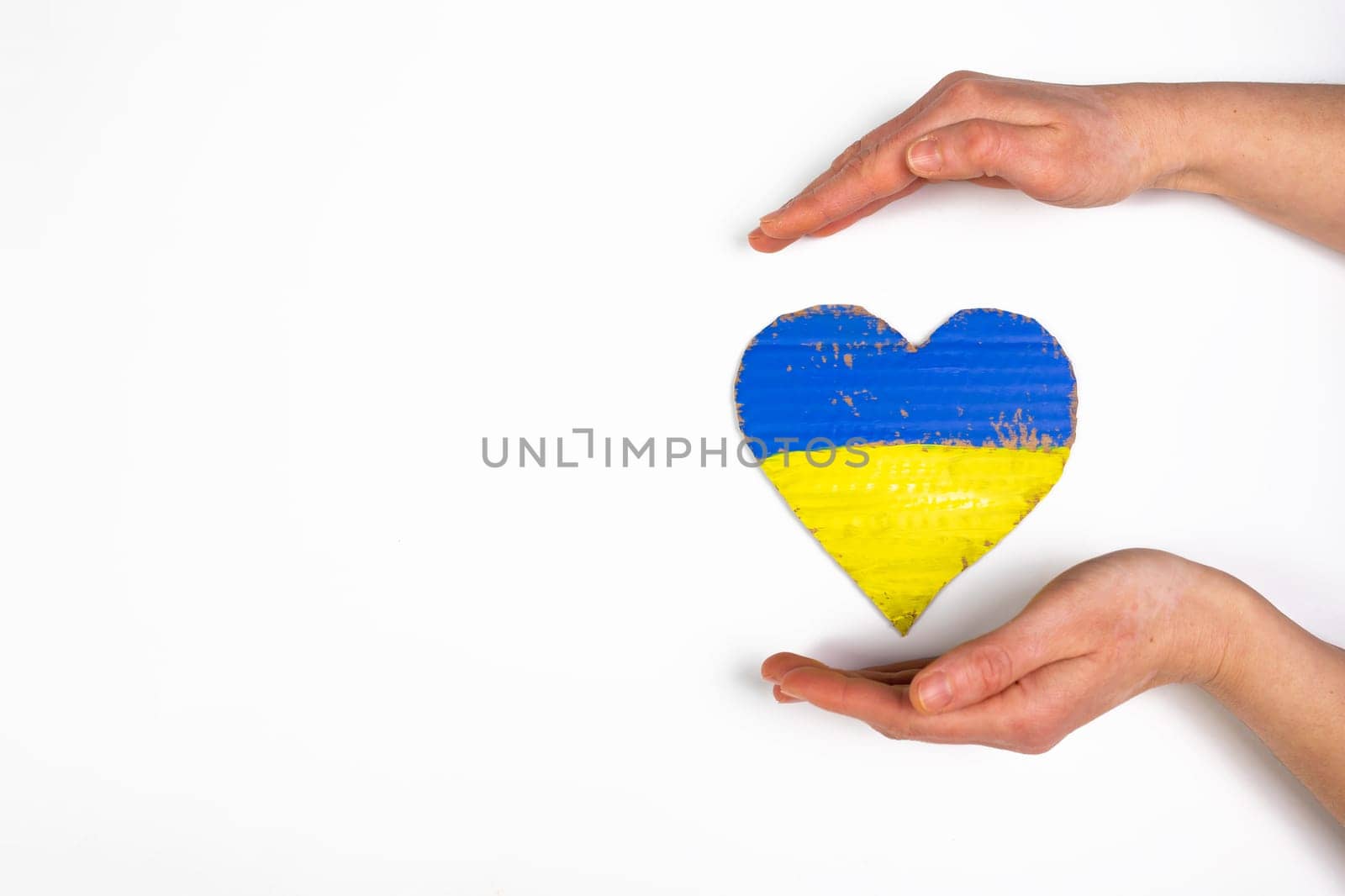 Heart shaped flag of Ukraine in female hands. The concept of solidarity with the citizens of Ukraine.