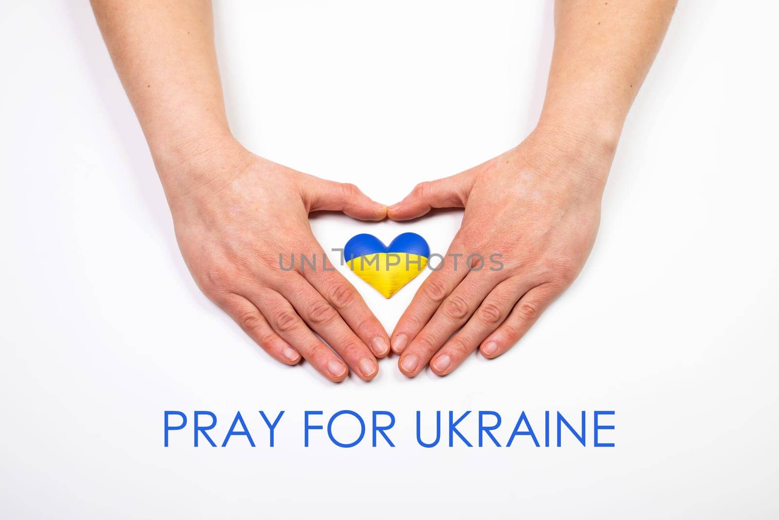 Heart shaped flag of Ukraine in female hands, Pray for Ukraine text.  The concept of solidarity with the citizens of Ukraine.