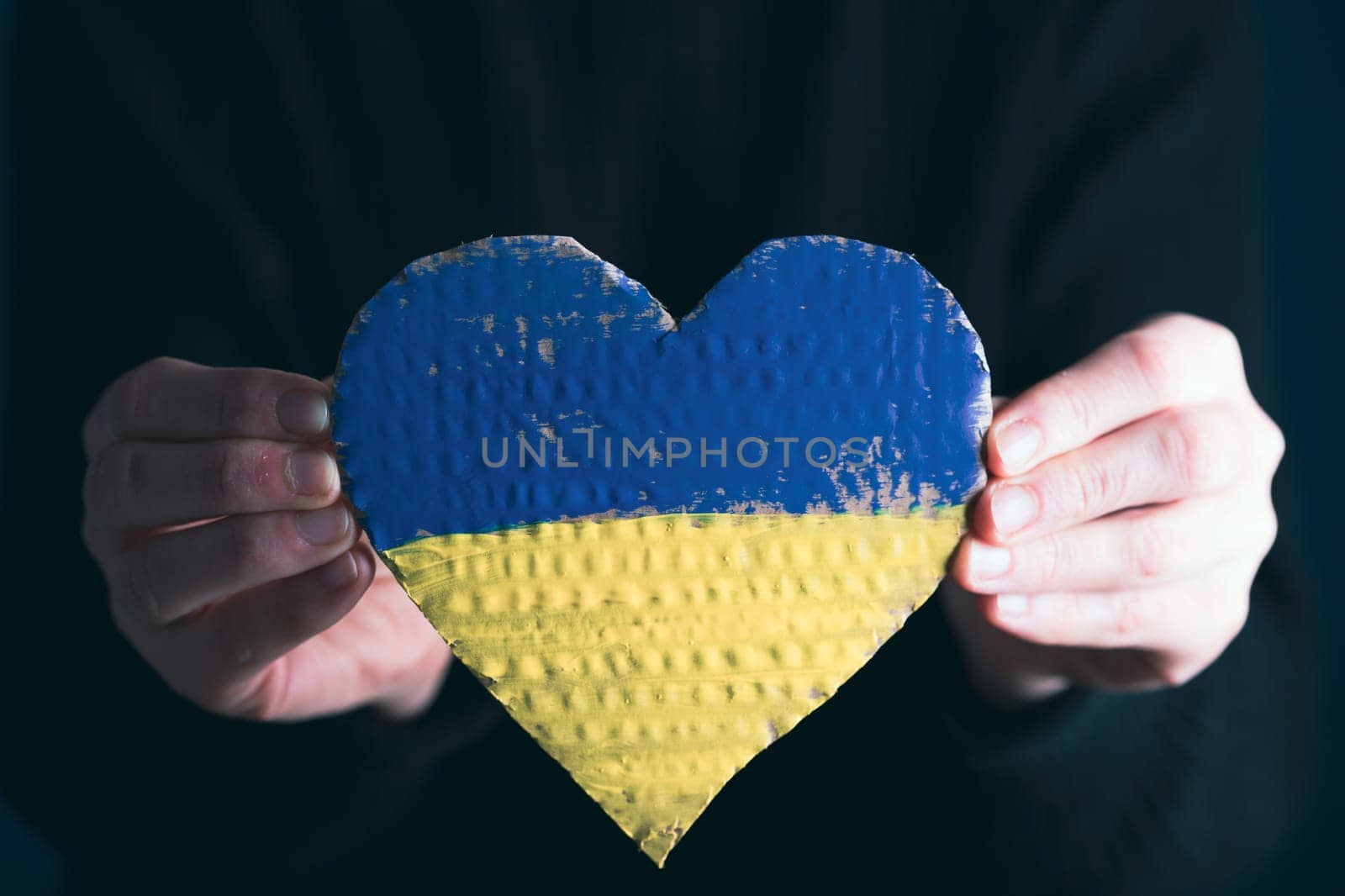 Heart shaped flag of Ukraine in female hands. The concept of solidarity with the citizens of Ukraine.