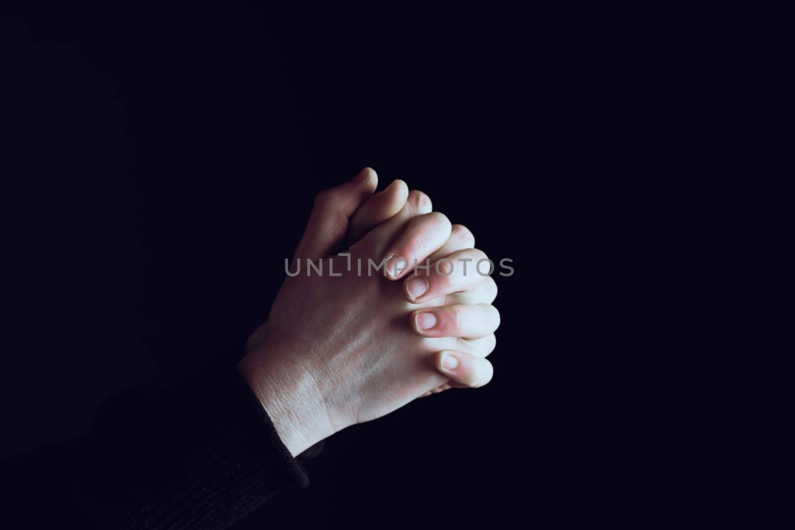Praying hands with faith in religion and belief in God on dark background. Power of hope or love and devotion.