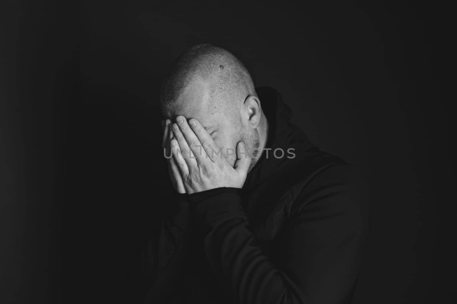 Sad man sitting in dark room. Depression and anxiety concept