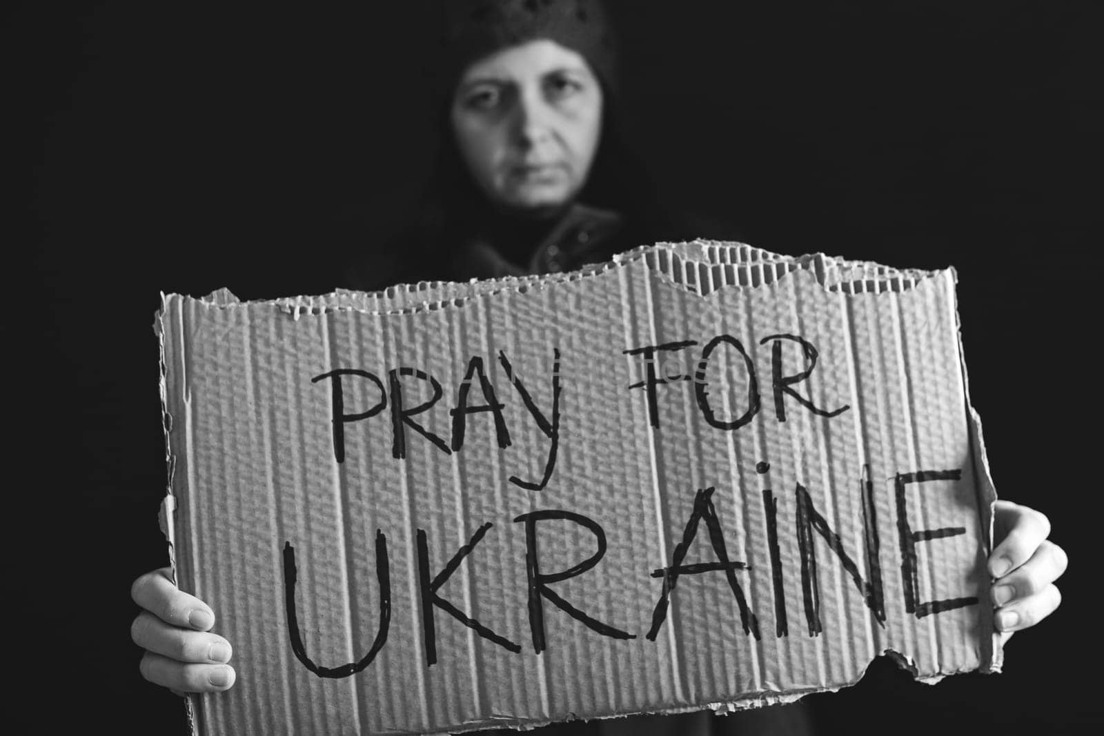 Woman holds a banner with anti-war message. Protest against the Russian intervention to Ukraine, activism and human rights movement. Concept of standing with Ukrainian.