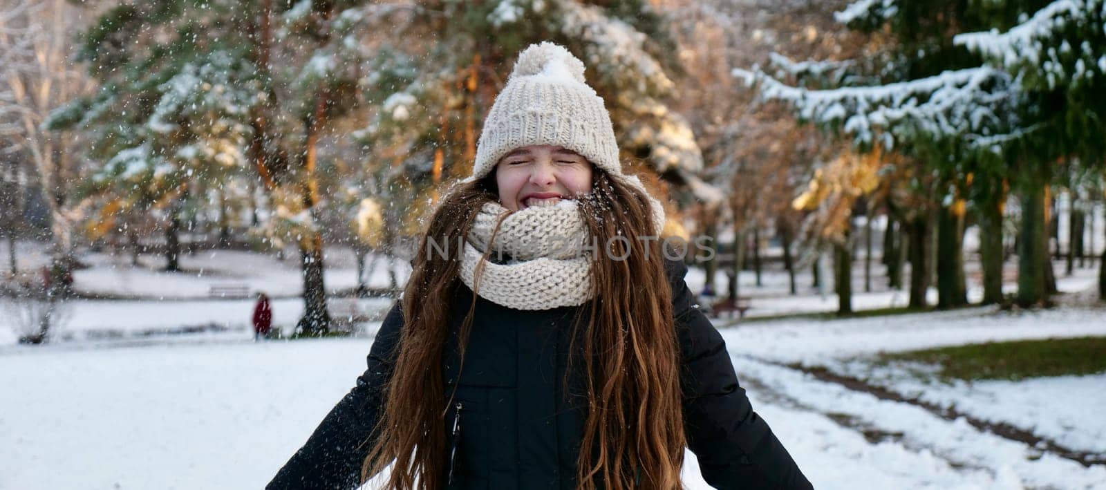 Young beautiful caucasian woman in winter close up in slow motion throws snow. Happy girl with long brown hair smiles on the eve of Merry Christmas and Happy New Year