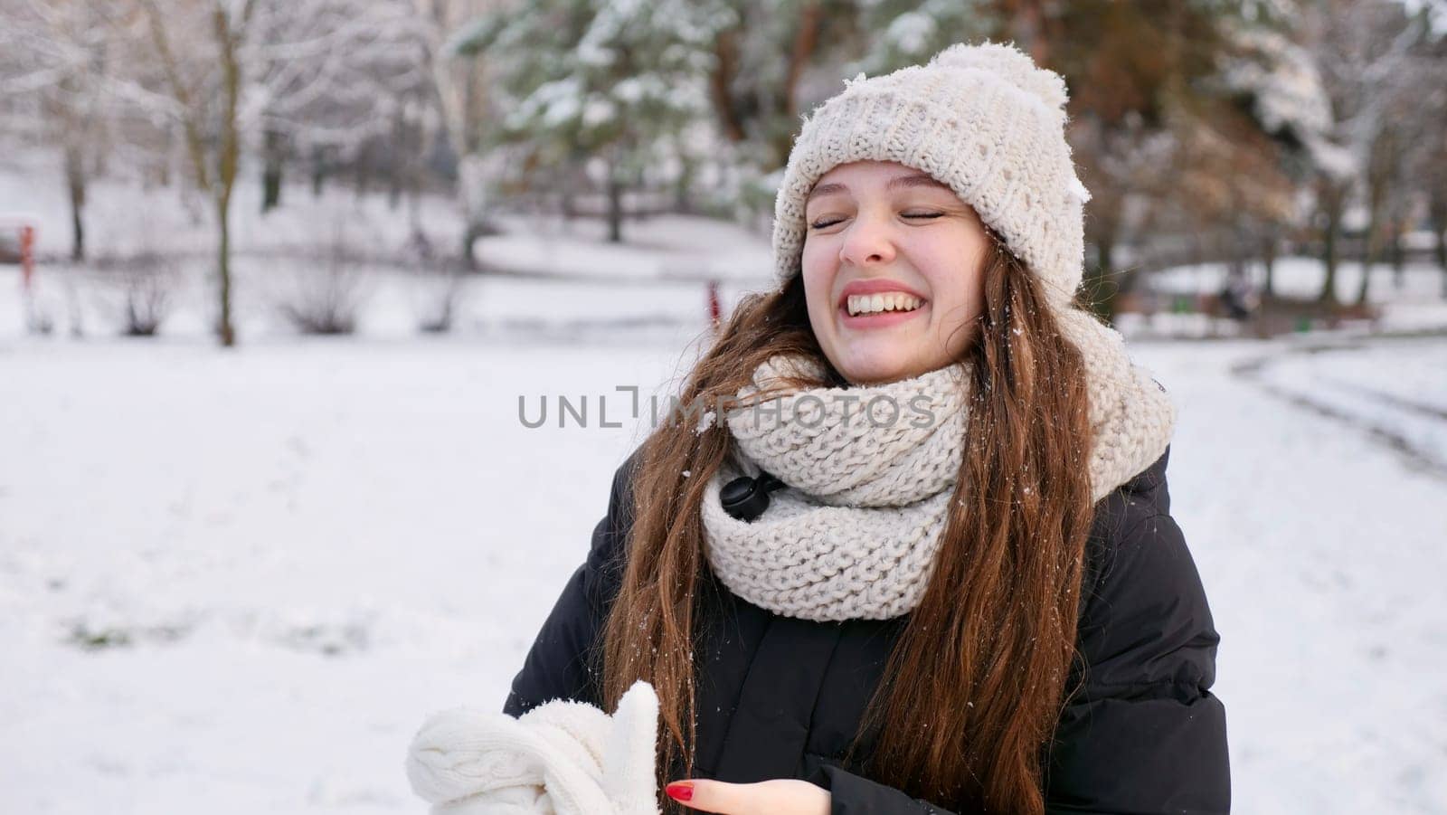 Young beautiful caucasian woman goulash in snowy winter forest close up in slow motion. Happy girl with long brown hair enjoys winter and smiles on Christmas Eve and Happy New Year