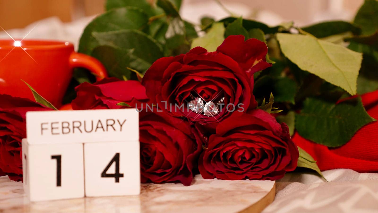 Background Festive Flatlay, composition for Valentine's Day on February 14. Coffee in a red cup, red rose flowers and diamond heart earrings at home in bed