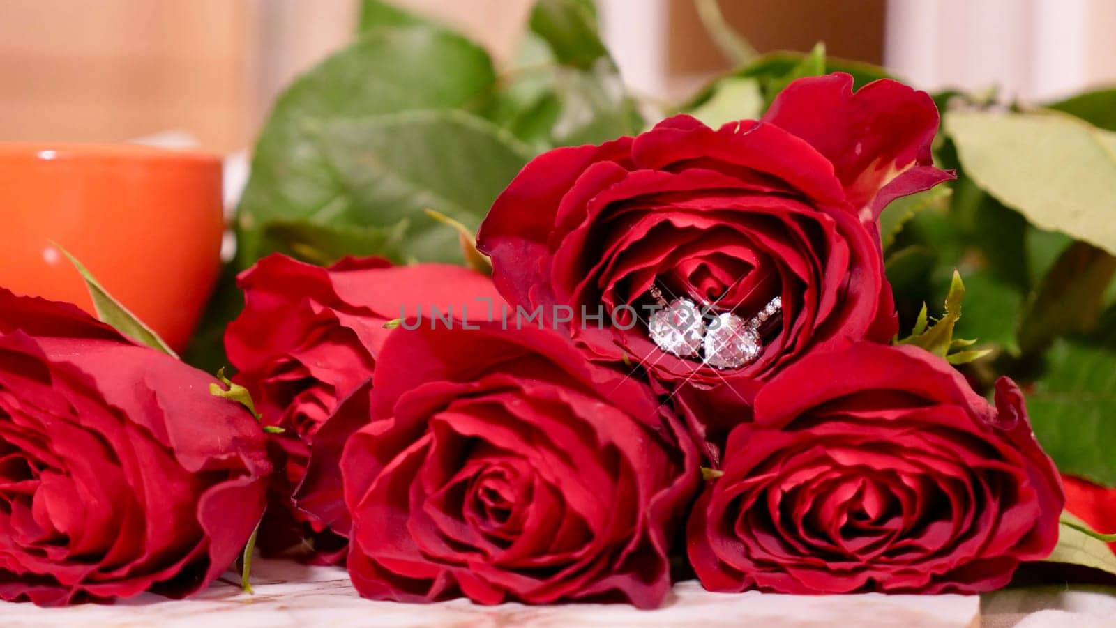 Background Festive Flatlay, composition for Valentine's Day on February 14. Coffee in a red cup, red rose flowers and diamond heart earrings