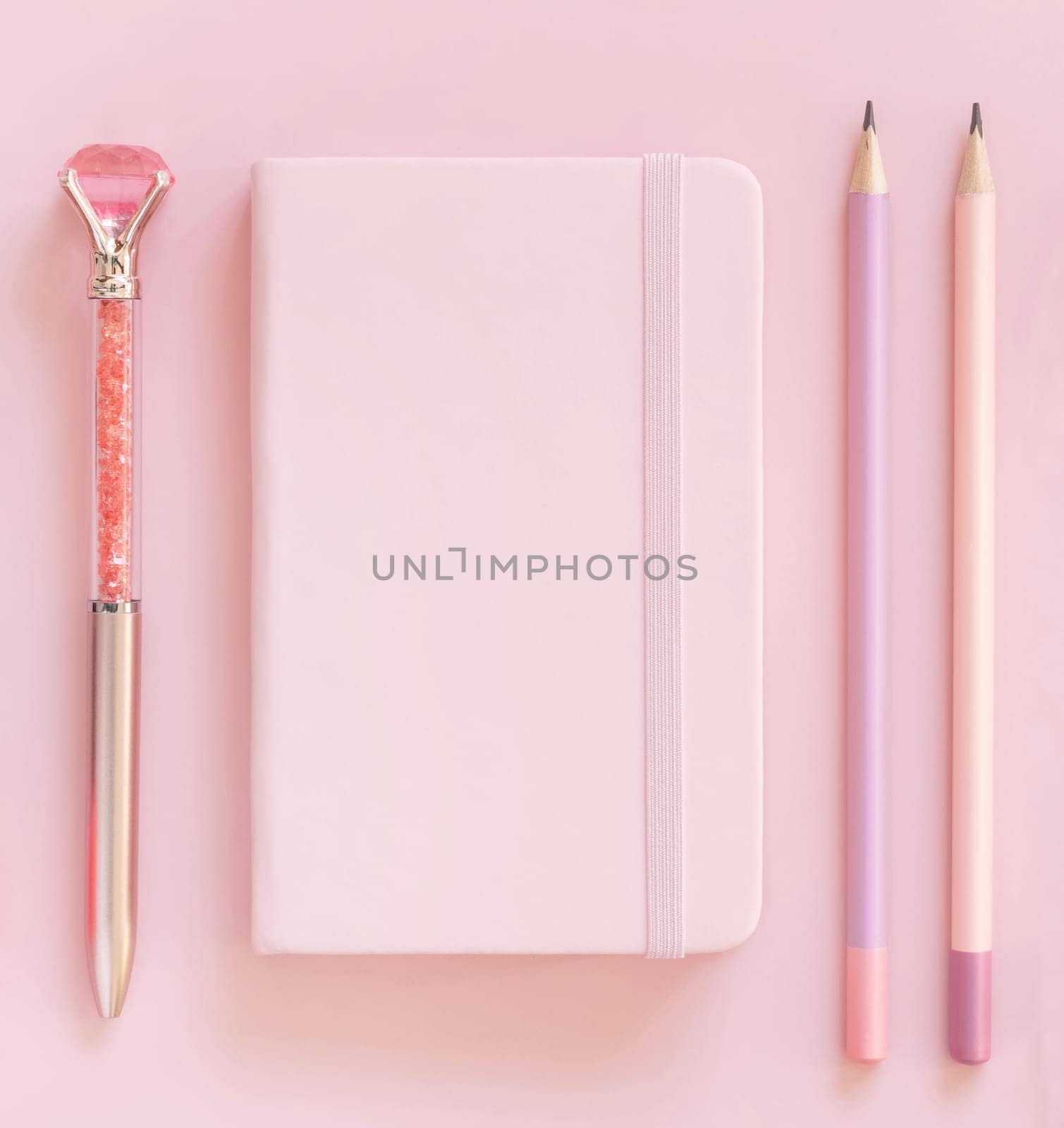 Pink notebook, pensils and decorative gemstone pen on light pink top view. Textbook mockup, planner cover with place fot text. Educational and girly concept