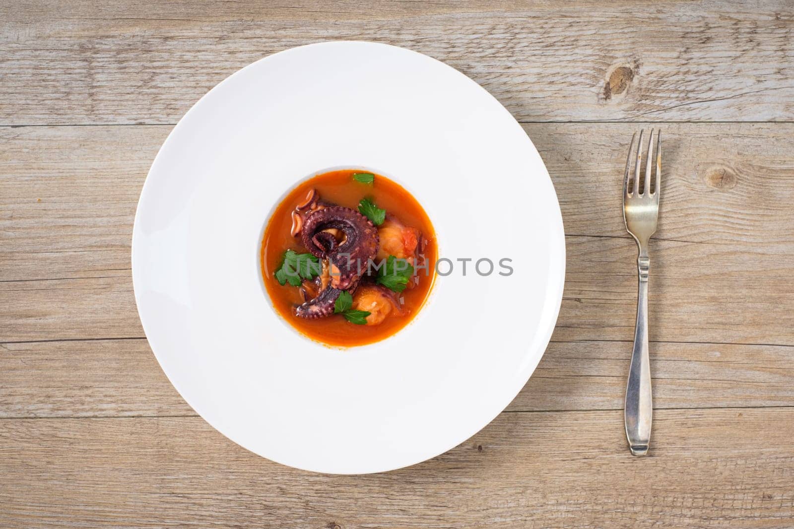 Plate on a table with braised octopus in tomato dish