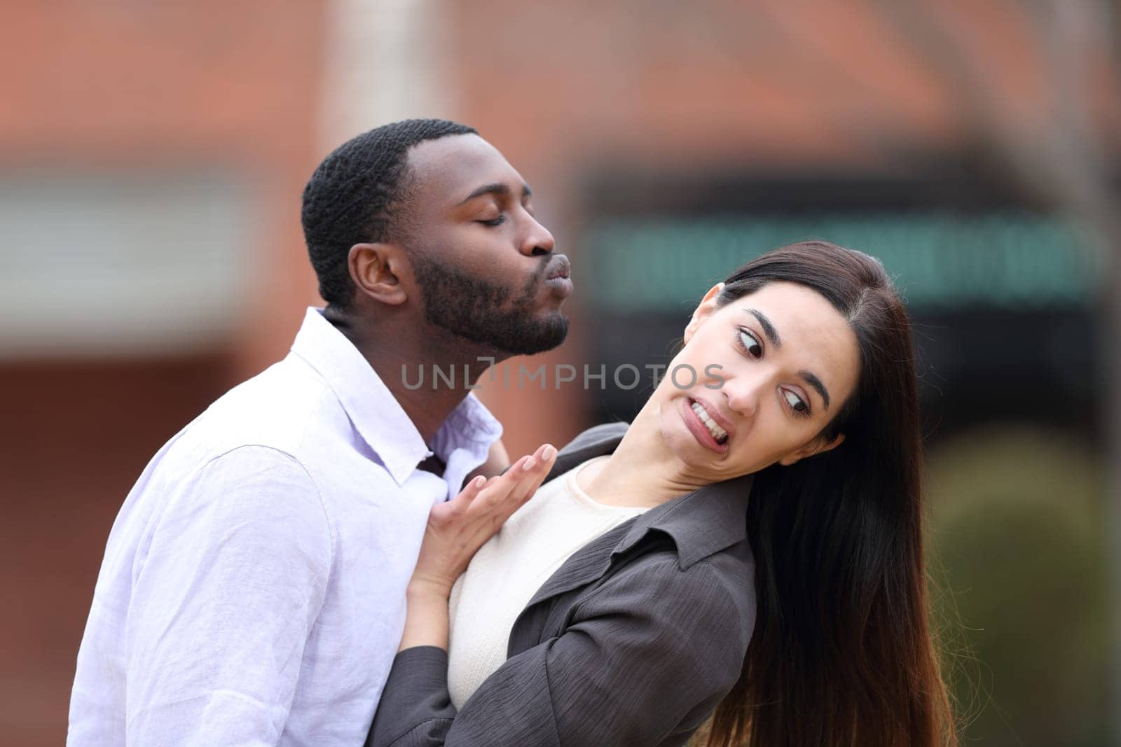 Man trying to kiss to a woman who is pulling him away