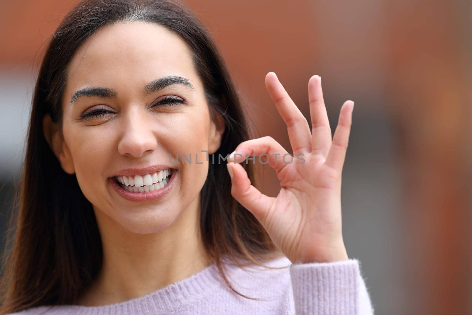 Happy woman gesturing ok sign in the street