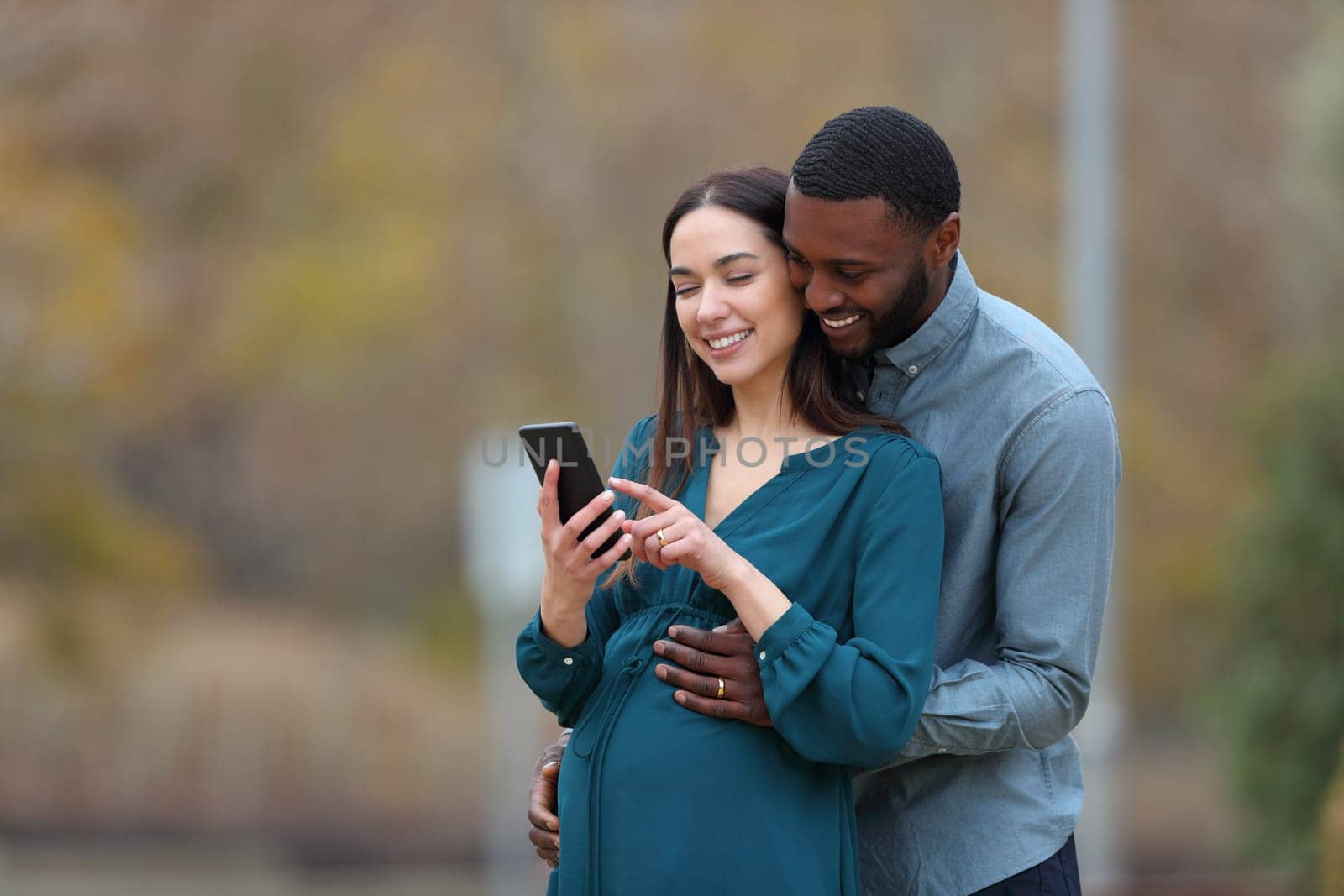 Pregnant wife and her husband checking smart phone