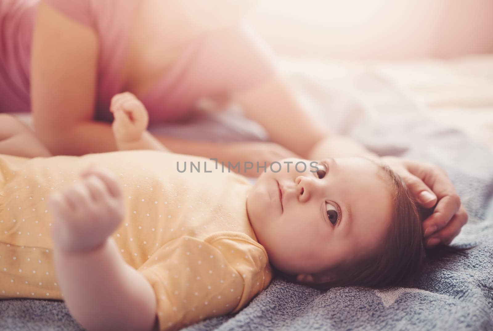 Happy mother with cute baby in bedroom. Concept of motherhood and parenting.