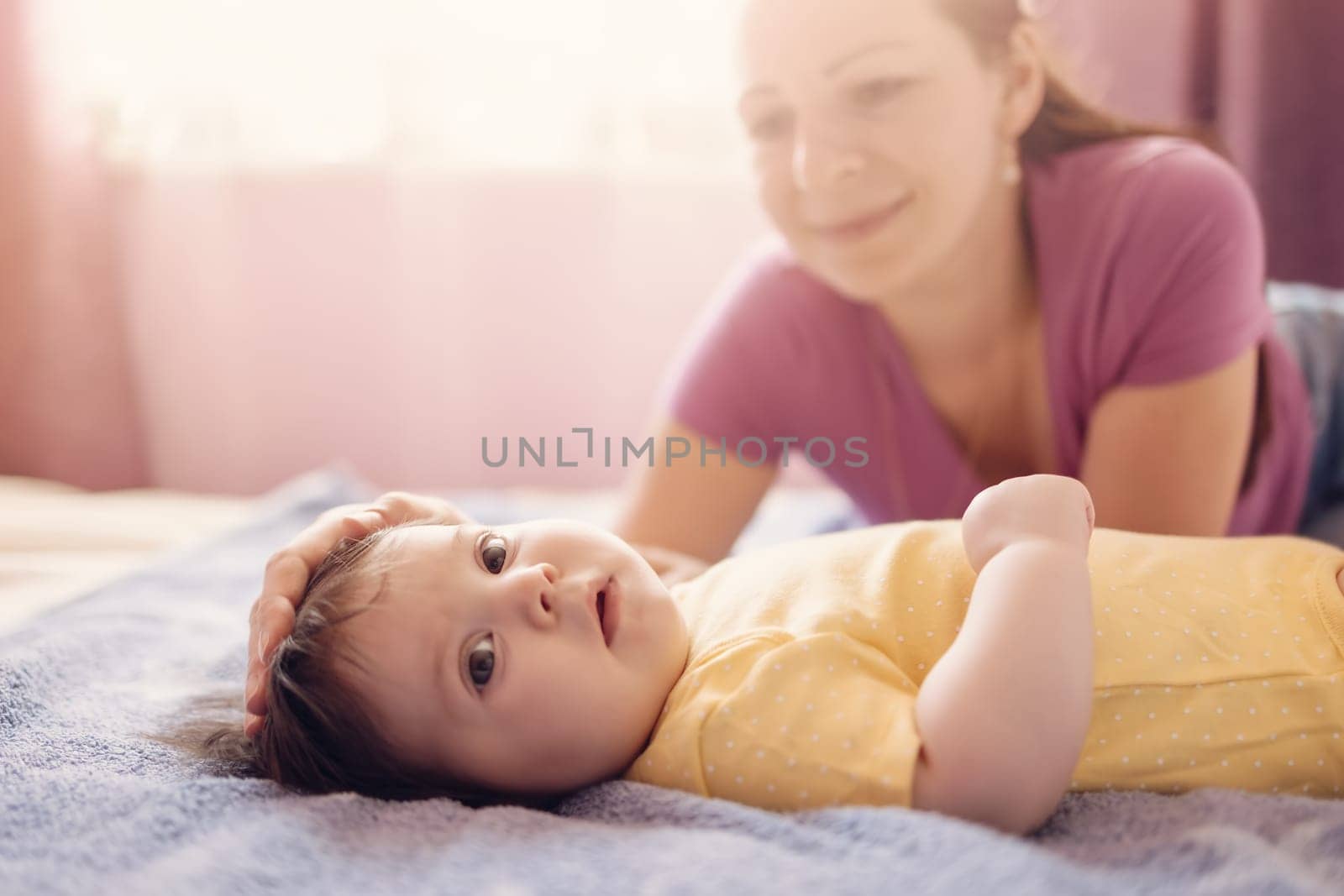Happy mother with cute baby in bedroom. Concept of motherhood and parenting.